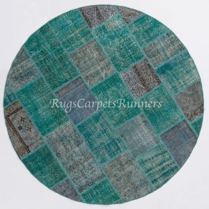 May include: A round patchwork rug with a teal and gray color scheme. The rug is made of various pieces of fabric sewn together in a diamond pattern. The rug is approximately 3 feet in diameter.