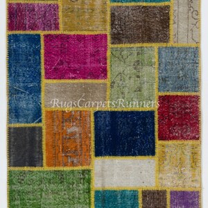 Pode incluir: Um tapete de patchwork colorido com uma variedade de cores e padrões, incluindo azul, verde, vermelho, amarelo e marrom. O tapete é feito de diferentes pedaços de tecido que foram costurados juntos. O tapete tem um aspecto desgastado, com algumas das peças de tecido mostrando sinais de desgaste.