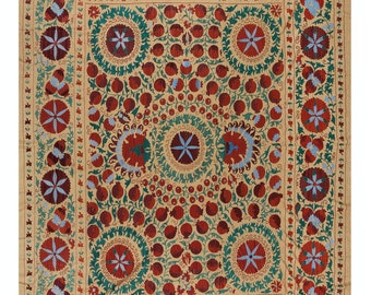 May include: A beige embroidered textile with a repeating pattern of red, blue, and green floral motifs. The design features a central circle with a starburst pattern surrounded by smaller circles and floral elements.