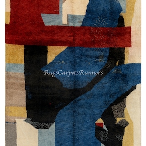 May include: Abstract area rug with geometric shapes in shades of red, blue, black, beige, and gray. The rug has a modern design and is perfect for adding a touch of color and style to any room.