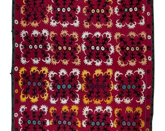 Könnte beinhalten: Ein roter Stoff mit einem sich wiederholenden Muster aus schwarzen, weißen und gelben Blumendesigns. Der Stoff ist mit bunten Details bestickt.