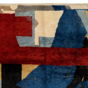 May include: Abstract geometric rug with a red, blue, beige, and black color scheme. The rug has a modern design with a variety of shapes and sizes.