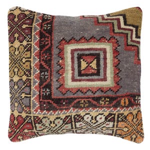 May include: Square decorative pillow with a vintage, patterned design. The pillow features a central square motif in red, green, and gray, surrounded by intricate borders in shades of brown, gold, and orange. The overall aesthetic is reminiscent of a traditional rug.