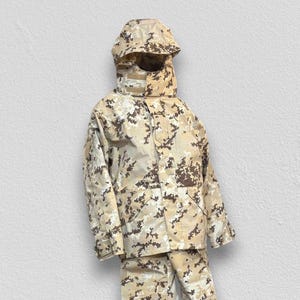May include: A tan and brown camouflage jacket, pants, and hood set. The jacket has a button-up front and pockets. The pants are loose-fitting. The hood is attached to the jacket and covers the head and neck.