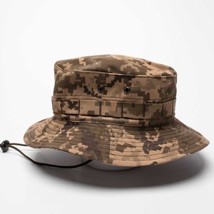 Könnte beinhalten: Ein brauner und tanfarbener Camouflage-Bucket-Hut mit einem schwarzen Kordelzug.