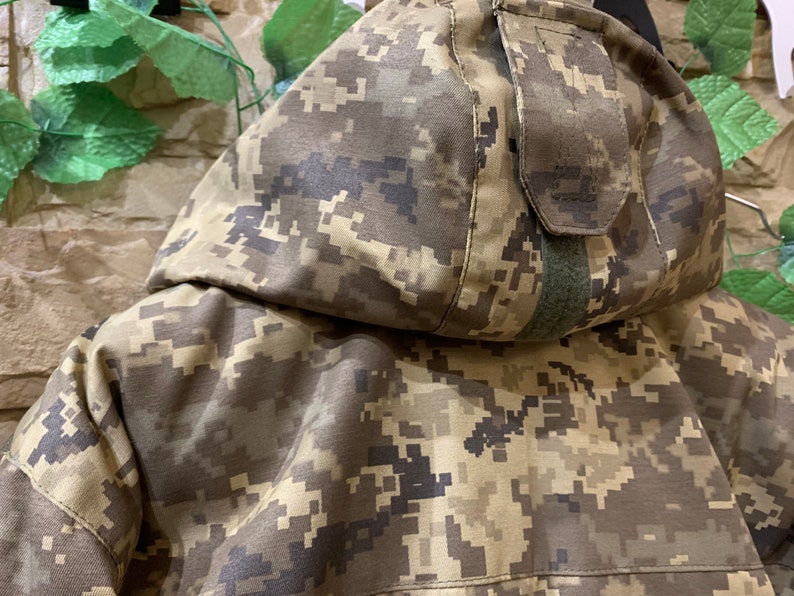 May include: A camouflage jacket with a hood and a zipper closure. The jacket is made of a durable, water-resistant fabric and features a variety of pockets.