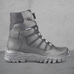 May include: A single black work boot with a high ankle and a rugged sole. The boot features a lace-up design with reinforced panels and the brand name "UBOTSHOES" is visible. The sole has the brand name "TREX" embossed.