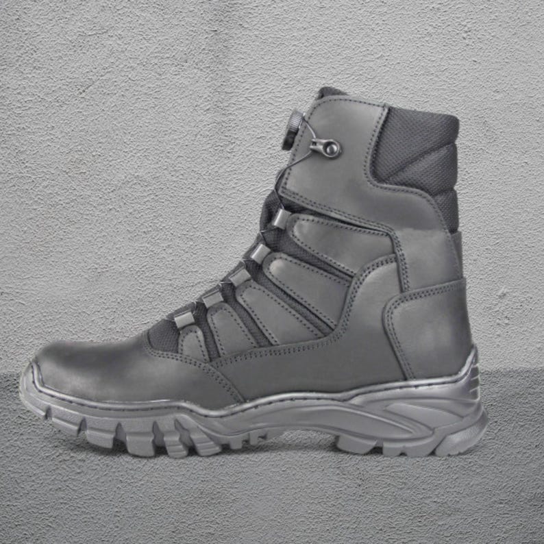 May include: A gray tactical boot with a high-top design. The boot features a rugged sole, a lace-up closure, and a padded collar. The boot is made of durable materials and is suitable for outdoor activities.