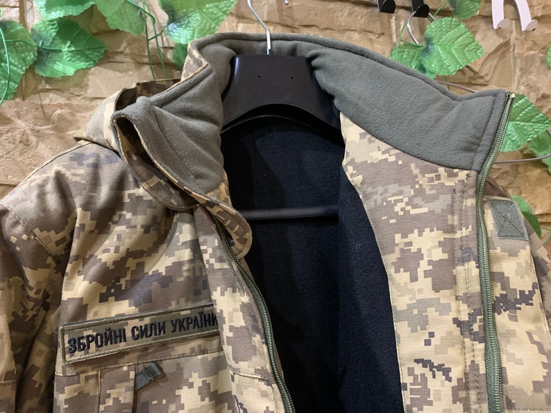 May include: A camouflage jacket with a black fleece lining and a zipper closure. The jacket has a hood and a patch that reads "Збройні Сили України".