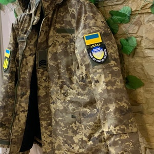 Left side view of Ukrainian Pixel MM-14 winter jacket, showing sleeve pocket, velcro panel and stitching details.