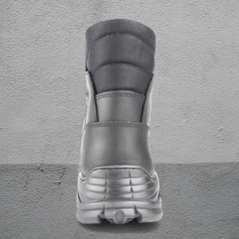 May include: A black combat boot with a padded collar and a textured sole. The boot has a smooth leather upper and a reinforced heel. The boot is designed for durability and protection.