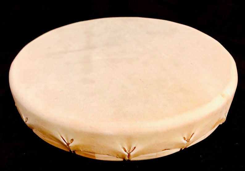 Op de afbeelding: Een ronde, lichtbruine leren trommel met een houten frame. De trommel is strak gespannen en klaar om te bespelen.