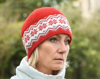 May include: A red knit beanie with a white and gray geometric pattern. The beanie is folded down over the wearer's forehead.