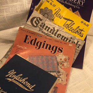 Peut inclure: Une pile de livres de modèles de crochet vintage avec des titres tels que "Hardanger Embroidery", "New Tablecloths", "Candlewick Crochet" et "Edgings". Les livres sont de différentes couleurs, notamment bleu, jaune et rose.