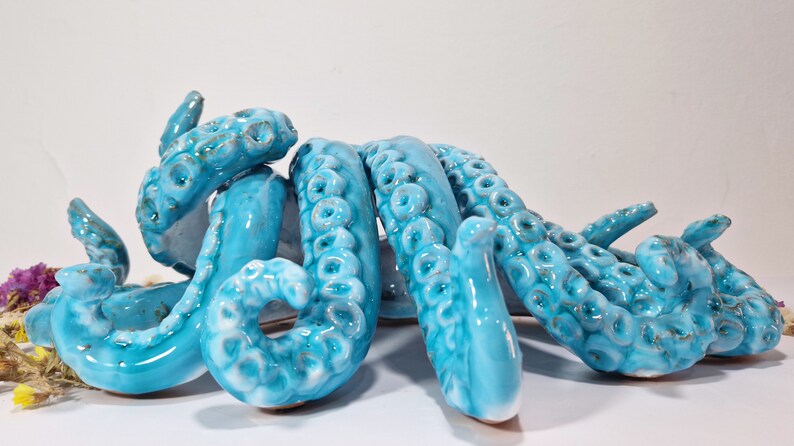 May include: A ceramic octopus sculpture with blue and white glaze. The octopus has eight tentacles with textured details.