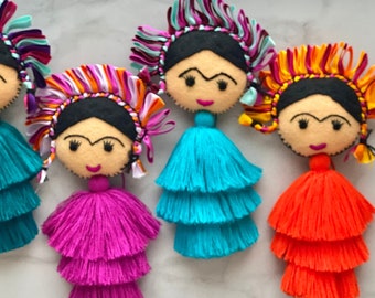 May include: Four colorful felt dolls with black hair and painted faces, each wearing a multi-colored ribbon headband and a layered tassel skirt in turquoise, pink, turquoise, and orange.