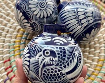 May include: Three blue and white ceramic ornaments with intricate designs. The ornaments feature a floral pattern, a bird design, and a geometric pattern. The ornaments are hand-painted and have a glossy finish.