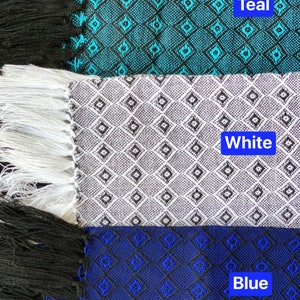 May include: Three fabric scarves with fringe edges. The top scarf is teal with a black and white diamond pattern. The middle scarf is white with a black diamond pattern. The bottom scarf is blue with a black diamond pattern. The text "Teal", "White", and "Blue" is printed on each scarf.