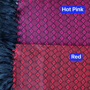 May include: A close-up of a fabric with a black and red diamond pattern. The top half of the fabric is hot pink and the bottom half is red. The fabric has black fringe on the left side.