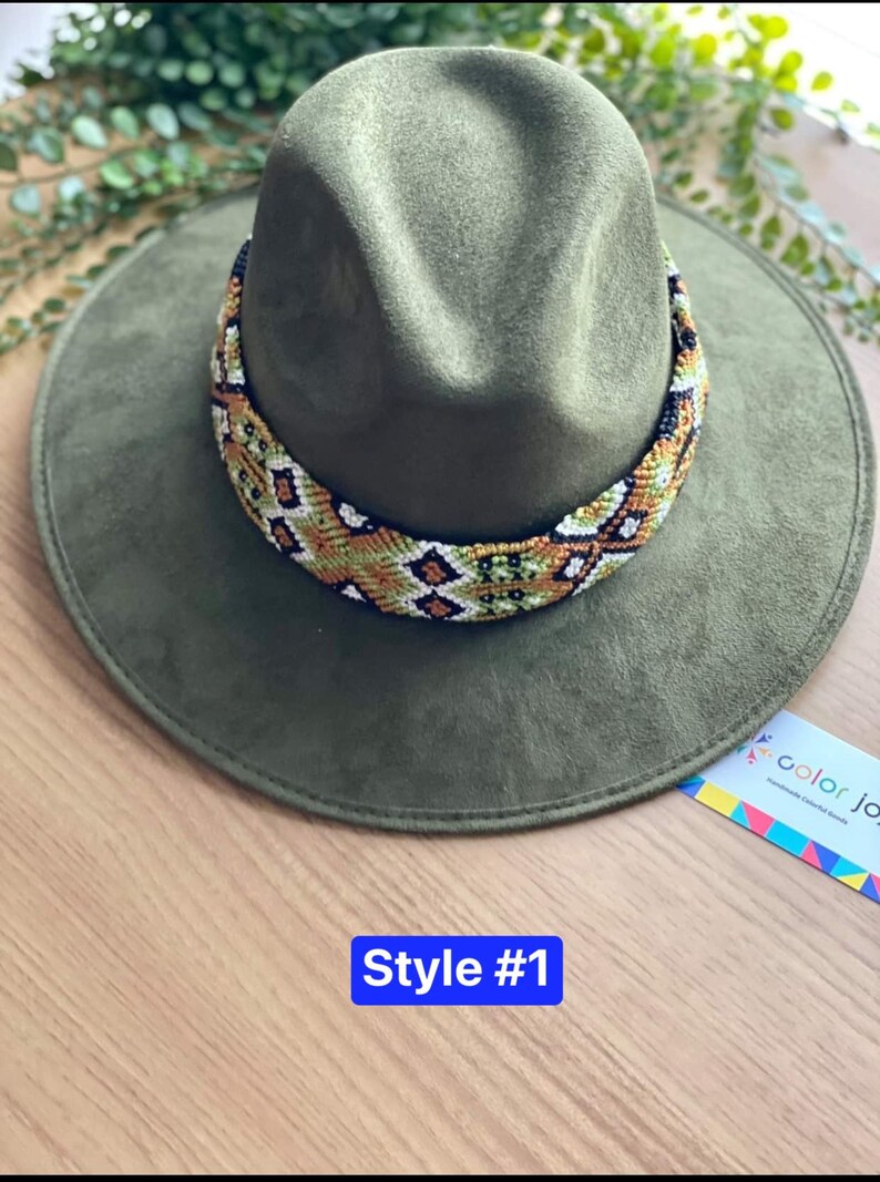 May include: A green felt fedora hat with a colourful beaded band. The band features a geometric pattern in shades of green, orange, white, and black. The hat is labelled "Style #1".