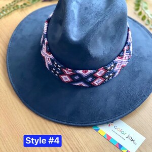 May include: A dark blue fedora hat with a colourful woven band. The band features a geometric pattern in shades of pink, purple, and blue. The hat is labelled "Style #4" and "color joy.co Handmade Colored Goods".