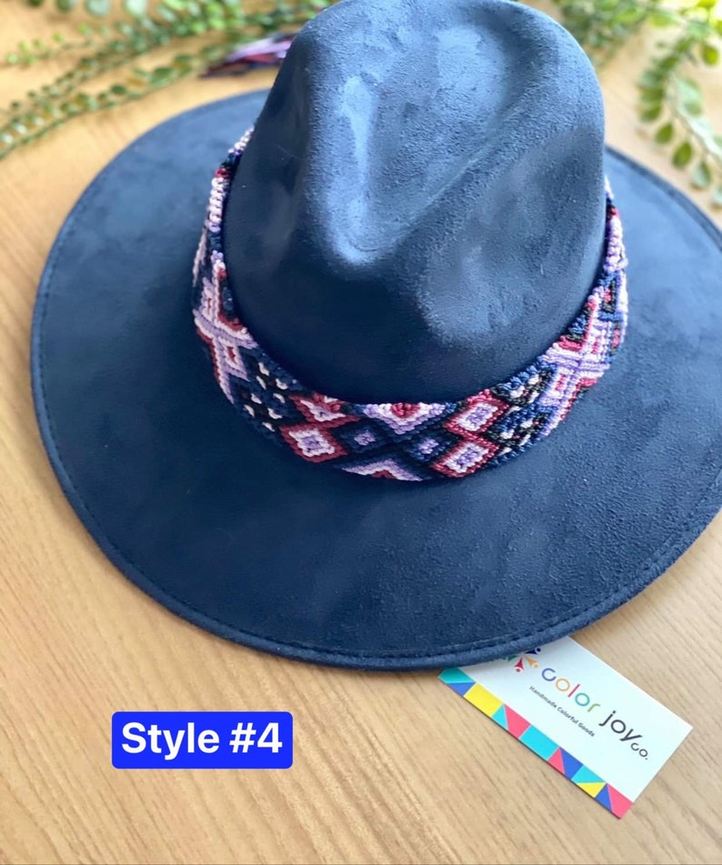 May include: A dark blue fedora hat with a colourful woven band. The band features a geometric pattern in shades of pink, purple, and blue. The hat is labelled "Style #4" and "color joy.co Handmade Colored Goods".