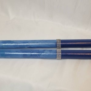 May include: Two cylindrical sticks featuring a gradient finish that transitions from a light blue at the ends to a deep navy blue. Each stick is accented with a band of silver-toned rhinestones positioned between the two blue color sections.
