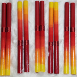 May include: Ten cylindrical wooden sticks arranged in pairs, each featuring a vertical color gradient transitioning from deep red at the top to bright yellow at the bottom, with two distinct bands of metallic red thread wrapped around the center.