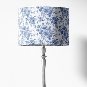 May include: A silver table lamp with a white lampshade featuring a blue floral pattern.
