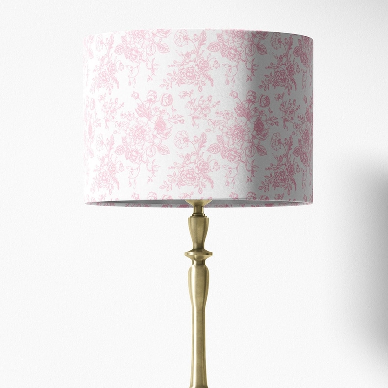 May include: A gold table lamp with a white lampshade featuring a pink floral pattern.