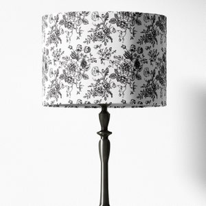 May include: A black and white floral lampshade with a black metal lamp base.