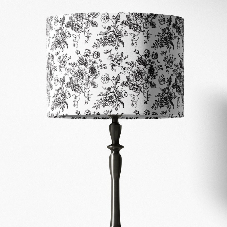 May include: A black and white floral lampshade with a black metal lamp base.