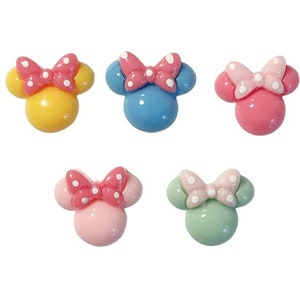 May include: Five colorful, cartoon-style Minnie Mouse head-shaped embellishments. Each has a round head and two smaller round ears. The bows are pink, with white polka dots. The heads are yellow, blue, pink, and green.