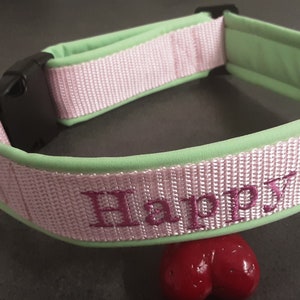 May include: A pink and green dog collar with the word "Happy" embroidered in pink.