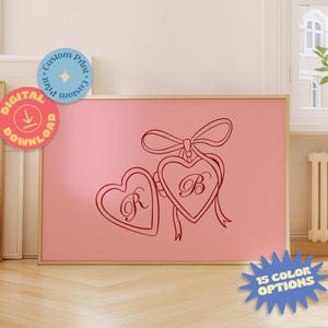 Könnte beinhalten: Gerahmter rosa Druck mit zwei herzförmigen Medaillons mit den Buchstaben "R" und "B", verbunden durch eine Schleife. Der Druck hat einen goldenen Rahmen und Aufkleber für digitalen Download und individuellen Druck.