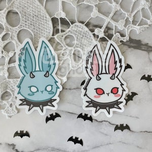 May include: Two sticker designs of cartoon bunnies with horns and spiked collars. The bunny on the left is blue with white eyes and the bunny on the right is white with red eyes.