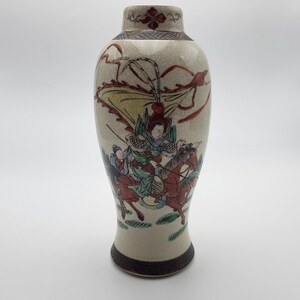 May include: A white ceramic vase with a crackled glaze and a hand-painted scene of a warrior on horseback. The scene is in shades of red, yellow, green, and blue.