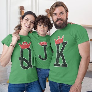 May include: A family of three wearing green t-shirts with a red crown and playing card design. The shirts say "Q", "J", and "K" with a crown above each letter.