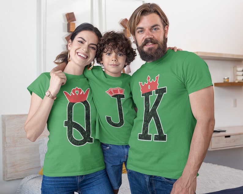 May include: A family of three wearing green t-shirts with a red crown and playing card design. The shirts say "Q", "J", and "K" with a crown above each letter.
