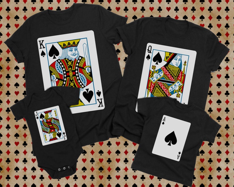 May include: A collection of black garments featuring playing card designs. One t-shirt displays a King of Spades, another a Queen of Spades, a third a smaller t-shirt with an Ace of Spades, and a black baby bodysuit featuring a Jack of Spades.