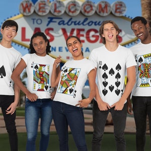 May include: A group of five white t-shirts featuring playing card designs. The shirts display an Ace of Spades, a Jack of Spades, a Queen of Spades, a ten of spades, and a King of Spades. Each shirt features the corresponding card suit and rank.