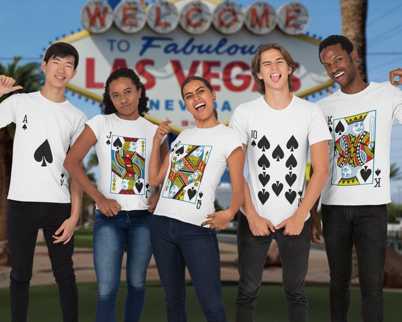 May include: A group of five white t-shirts featuring playing card designs. The shirts display an Ace of Spades, a Jack of Spades, a Queen of Spades, a ten of spades, and a King of Spades. Each shirt features the corresponding card suit and rank.