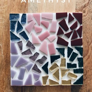 Puede incluir: Un posavasos cuadrado hecho de peque&ntilde;os trozos de vidrio en tonos de morado, rosa, burdeos, dorado y verde. El posavasos est&aacute; etiquetado con "AMETHYST" en texto blanco.