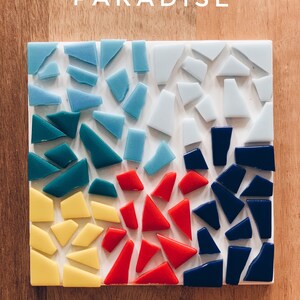 Puede incluir: Un posavasos cuadrado de mosaico con fondo blanco y cuatro secciones de piezas de vidrio de diferentes colores. Las secciones son azules, verde azulado, rojas y azul oscuro.
