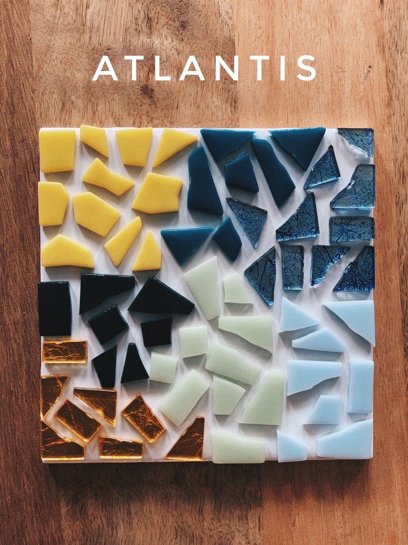 Puede incluir: Un azulejo de mosaico cuadrado con fondo blanco y un dise&ntilde;o de varias piezas de vidrio de colores. Los colores incluyen amarillo, azul, verde, negro y dorado. El azulejo est&aacute; etiquetado como "ATLANTIS".