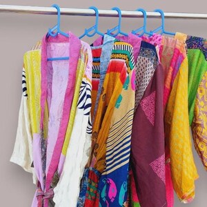 Może przedstawiać: Kolekcja kolorowych, wzorzystych jedwabnych szat wiszących na wieszakach. Szaty są wykonane z różnych tkanin i mają różne długości. Szaty są wszystkie w odcieniach różowego, żółtego, niebieskiego, zielonego i czerwonego.