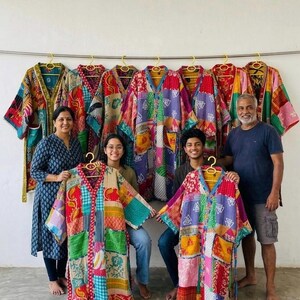 May include: A collection of colorful, patchwork kimonos hanging on a wall, with a family holding two of the kimonos. The kimonos feature a variety of patterns and colors, including red, green, blue, and yellow. The kimonos are made of a soft, lightweight fabric.