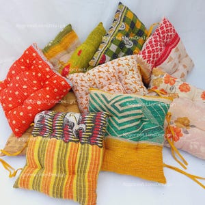 May include: A collection of nine colourful, square, quilted floor cushions with various patterns. The cushions are made from recycled saris and have a unique, vintage look.
