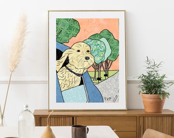 May include: A framed art print featuring a dog with its head out of a car window. The dog is light tan with a blue collar. The background includes trees, a road, and an orange sky. The print is displayed on a wooden cabinet.