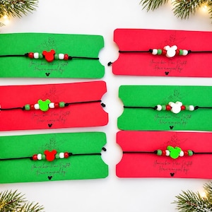 May include: Six black cord bracelets with colorful beads, including a central mouse-shaped bead, mounted on red or green rectangular cards. Each card features the printed text: You've been Pixie Dusted! Have a magical day! with a small mouse icon.